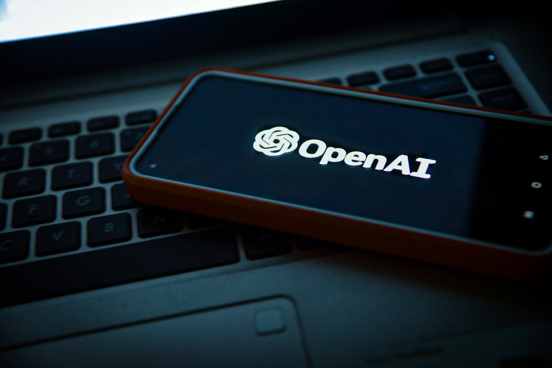 Uno smartphone con il logo OpenAI poggia su una tastiera di laptop.