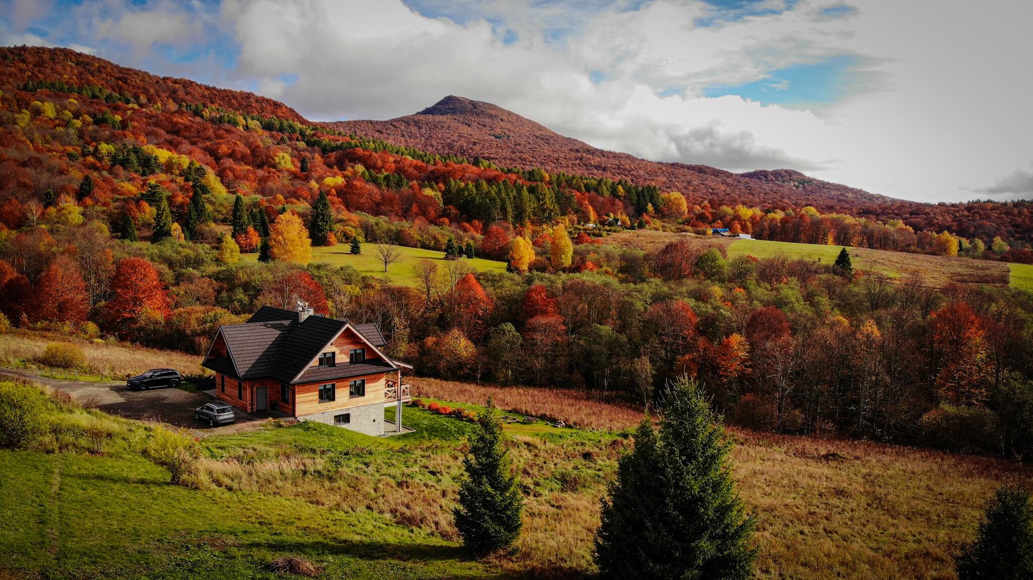 Vue sur une maison à Bukowe Tarasy entourée d'arbres d'automne et de montagnes.
